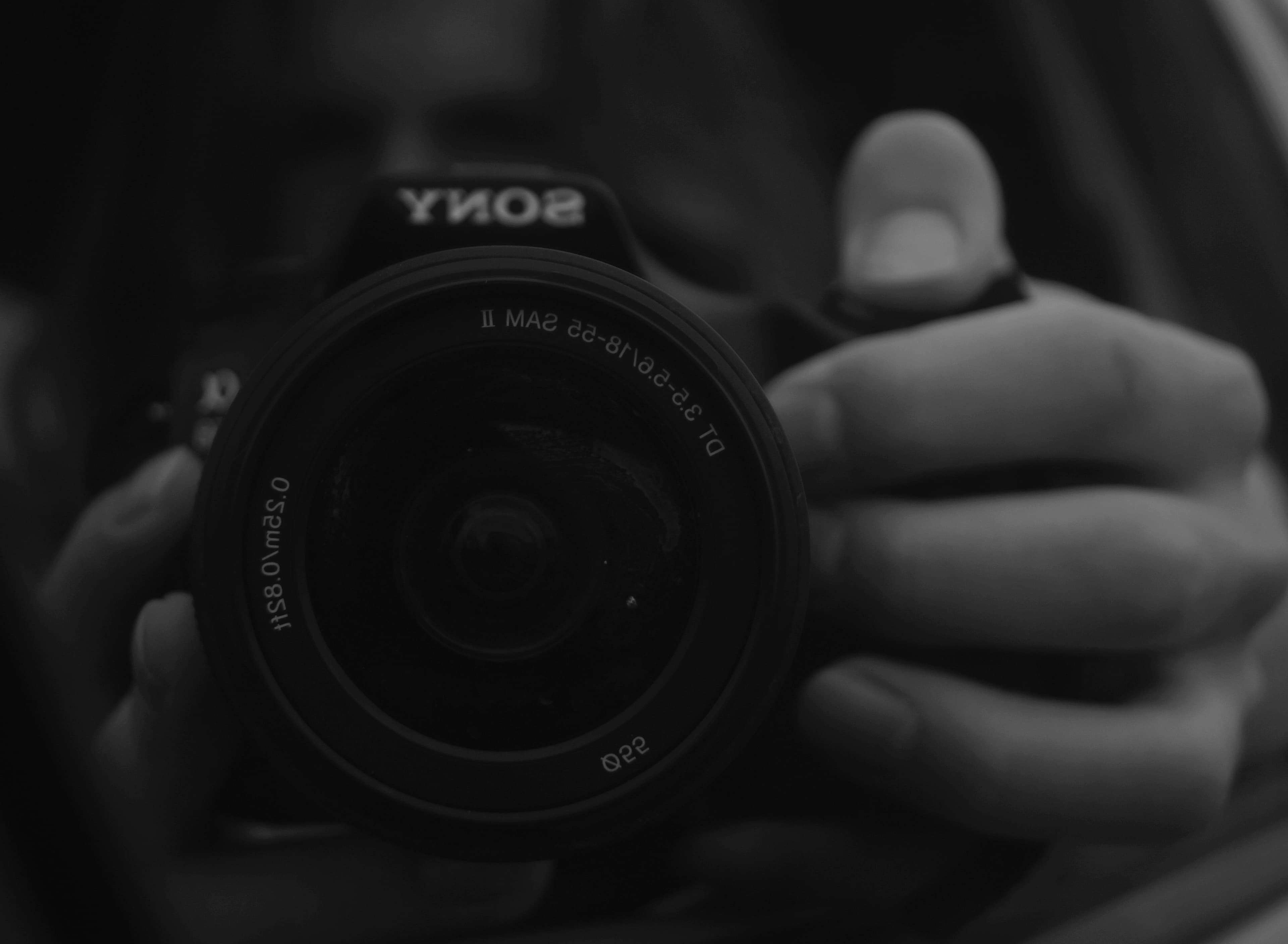 Black and white close-up of a Sony DSLR lens held by Levi Bouma