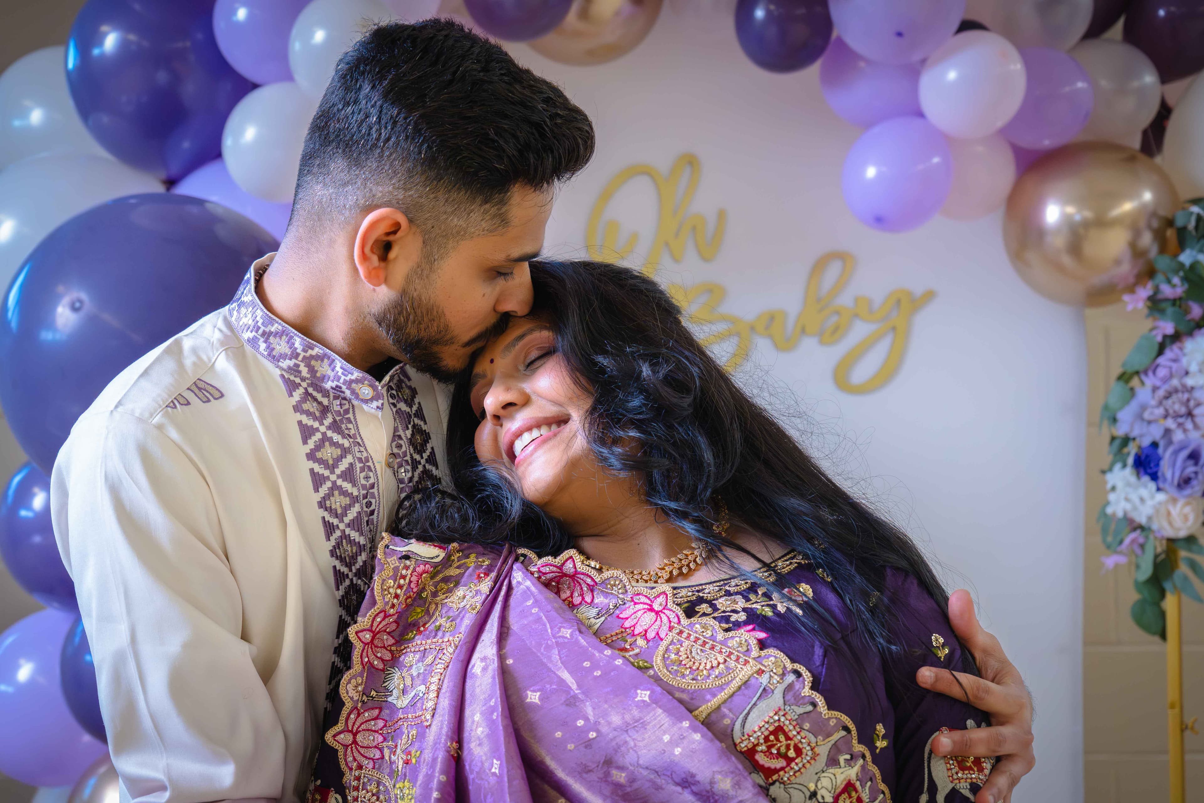 Couple sharing a tender moment under an Oh Baby sign — maternity celebration in London, Ontario