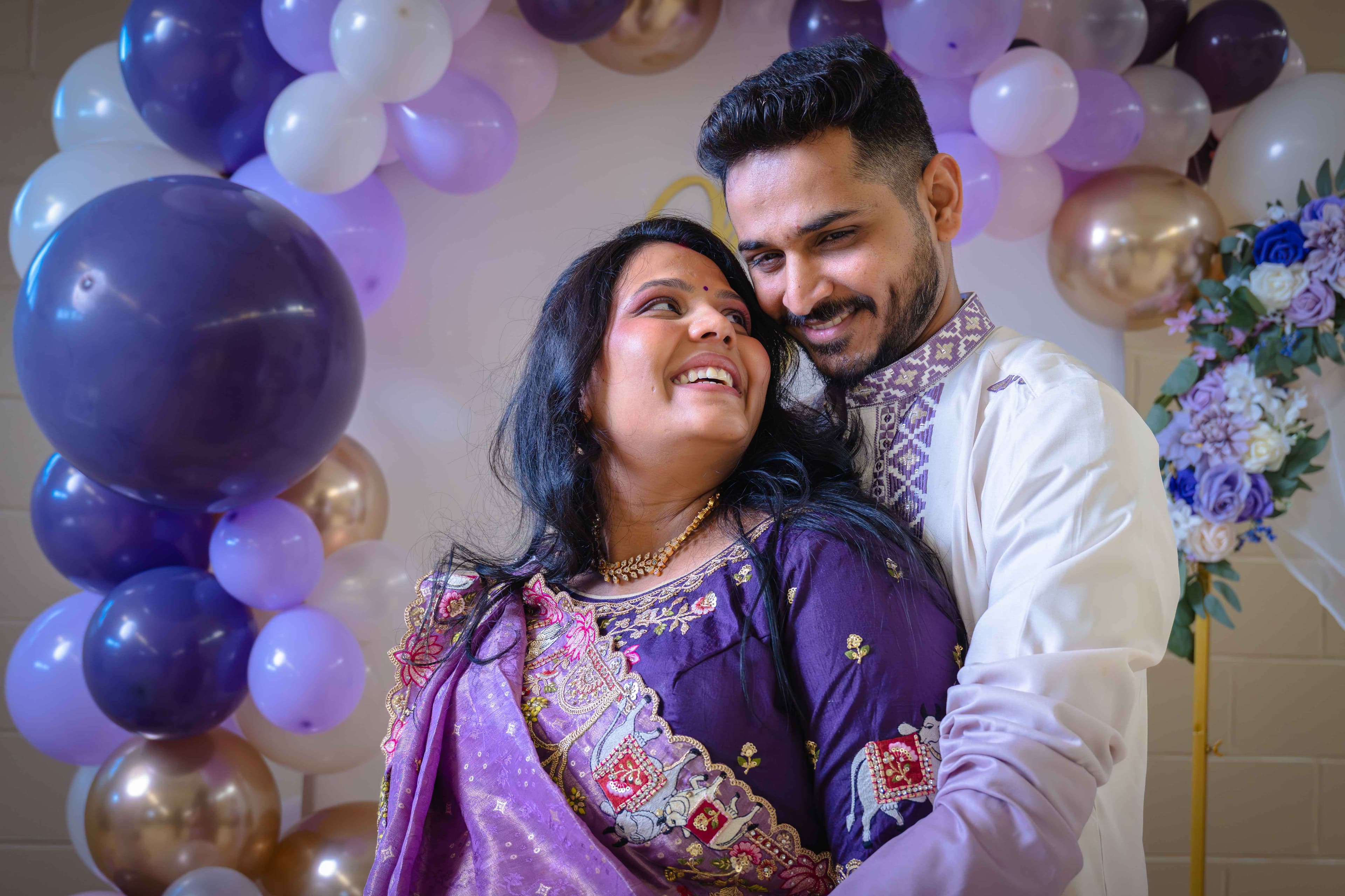 Couple laughing together surrounded by purple and white balloons