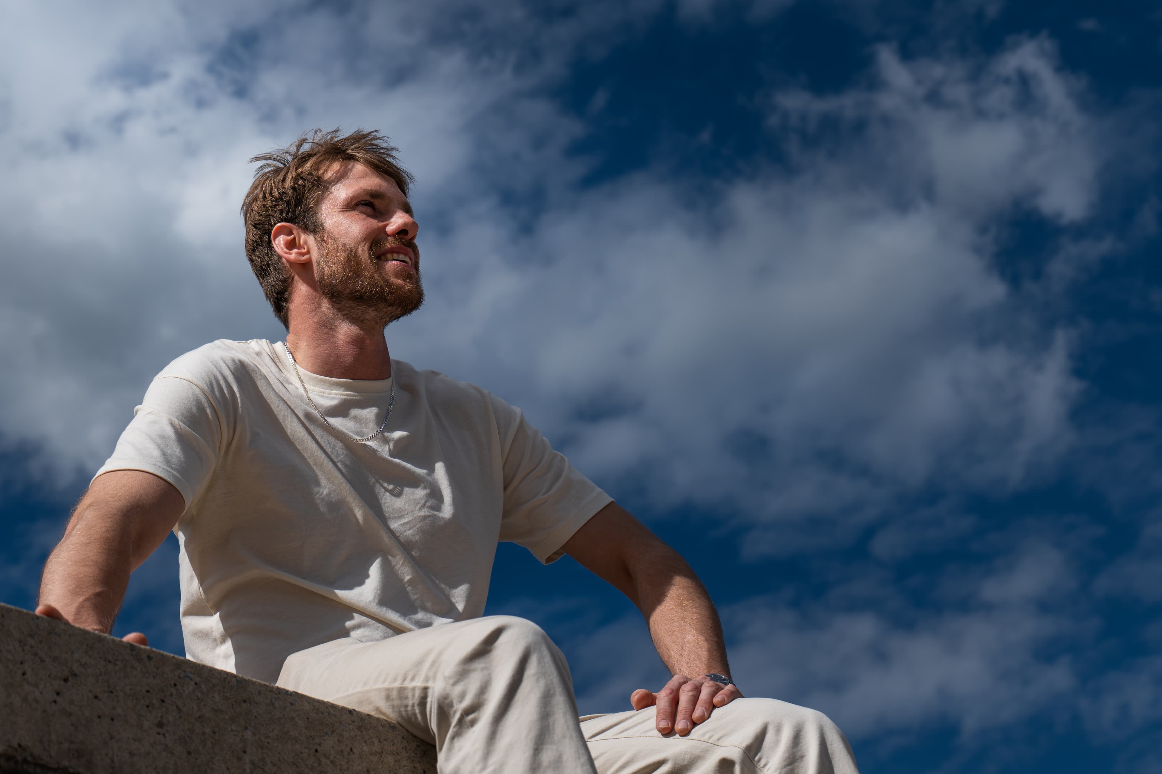 Low-angle portrait of a young man against a dramatic cloud-filled sky