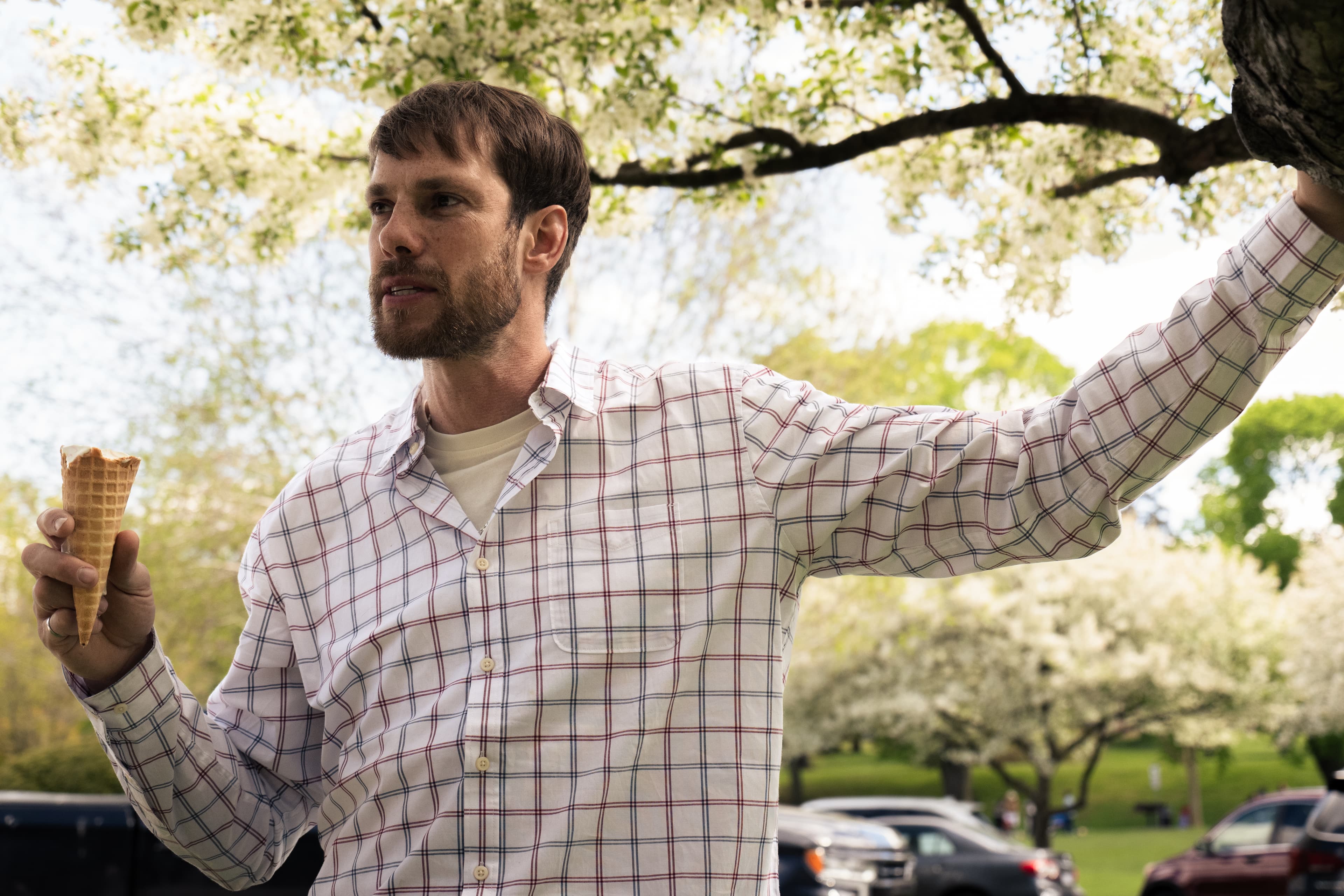 Man holding an ice cream cone under a blossoming tree